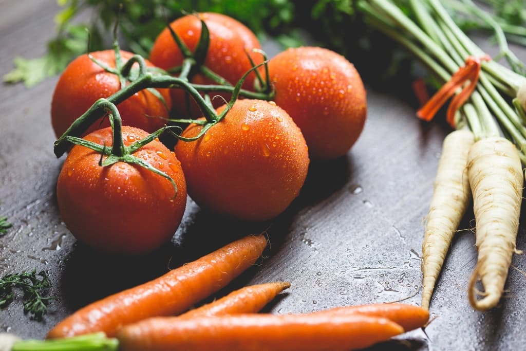 Tomates, zanahorias y chirivías sobre una mesa.